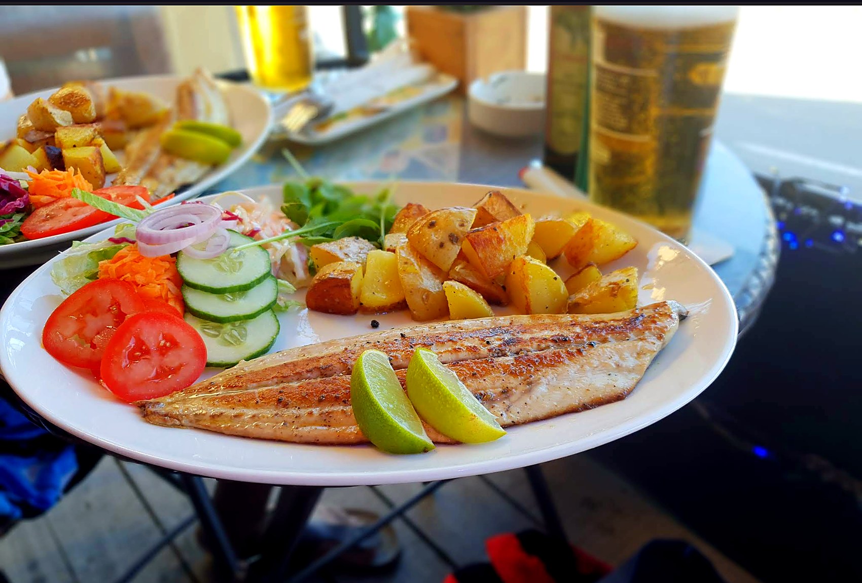 Grilled fish with potatoes, salad and lemon.