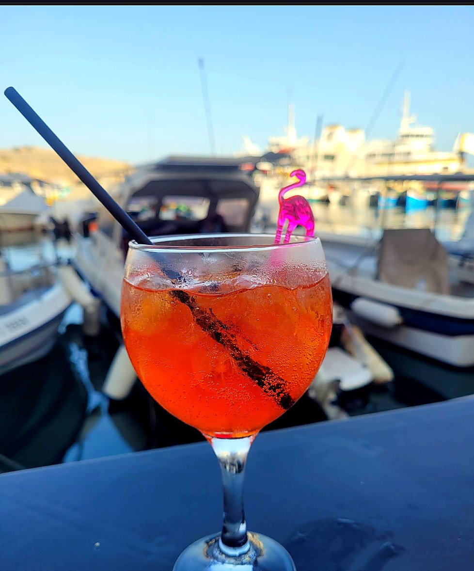 A spritz on a table with boats in the background.