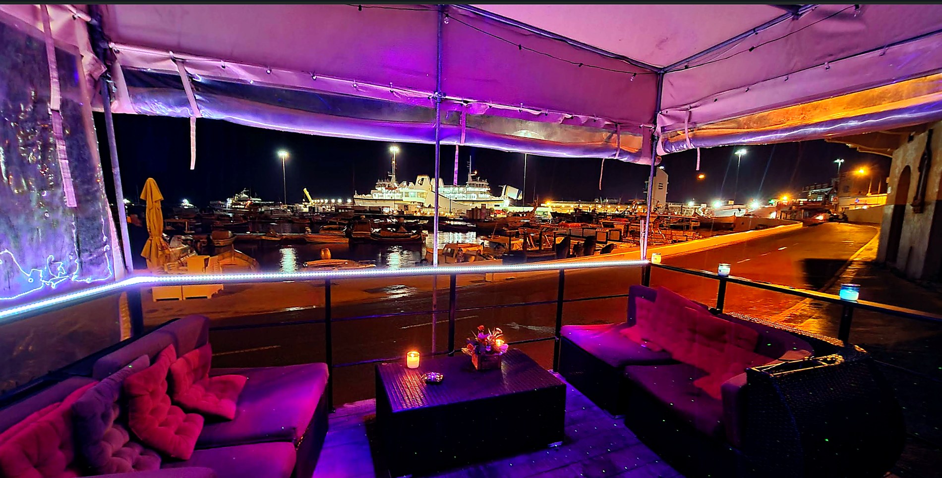 Il-Luzzu terrace seating at night with harbour lights.